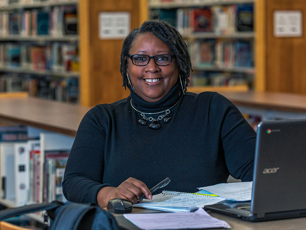 Adult-Student-Sitting-at-Desk-Smiling-at-Camera-Featured