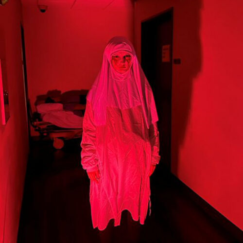 Spooky-Person-Standing-in-a-Red-Lit-Hallway-Featured